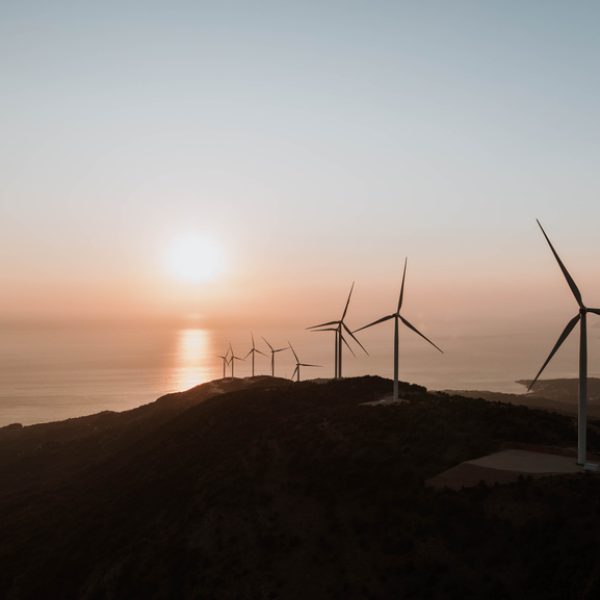 Aerial view of wind turbines on the hill close to the Adriatic sea in Montenegro. Forest aerial view. Reduce and account for emissions in your climate disclosure and sustainability reporting using NZCS1, TCFD, IFRS S2, for climate related financial disclosures.